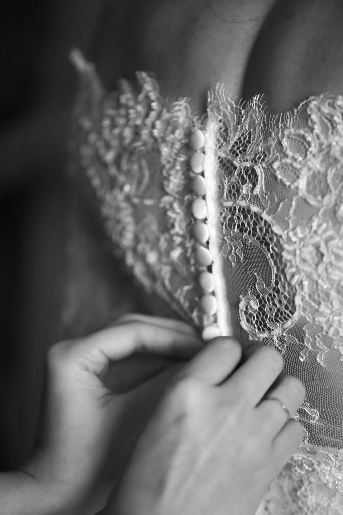 Nahaufnahme von Händen die das Brautkleid zuknöpfen