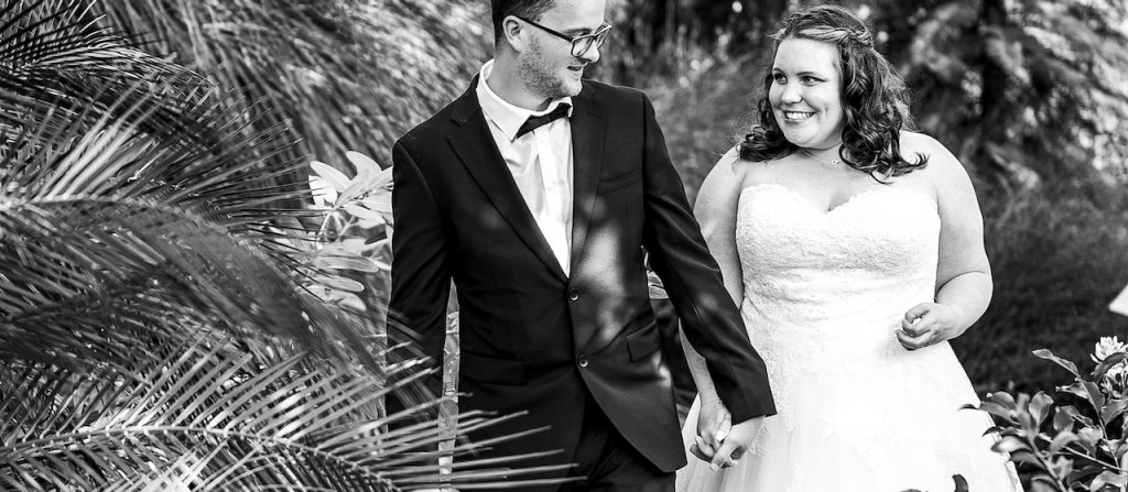 Brautpaar Hand in Hand zwischen Blumen