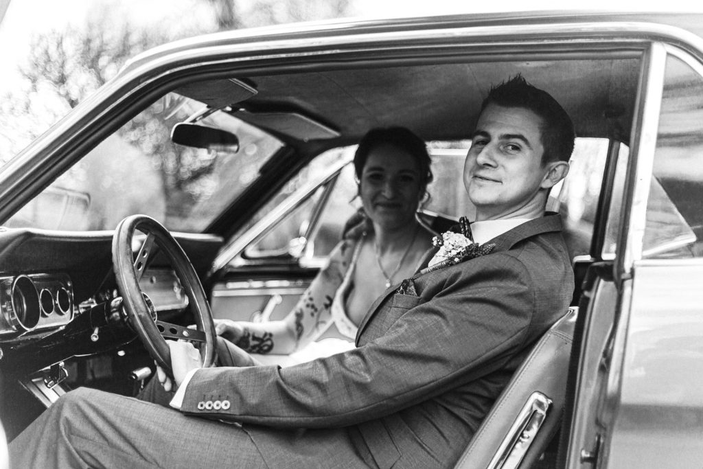 Foto eines Brautpaares im Oldtimer sitzend am Hochzeitstag