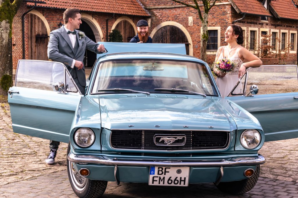 Foto eines Brautpaares im Oldtimer am Hochzeitstag